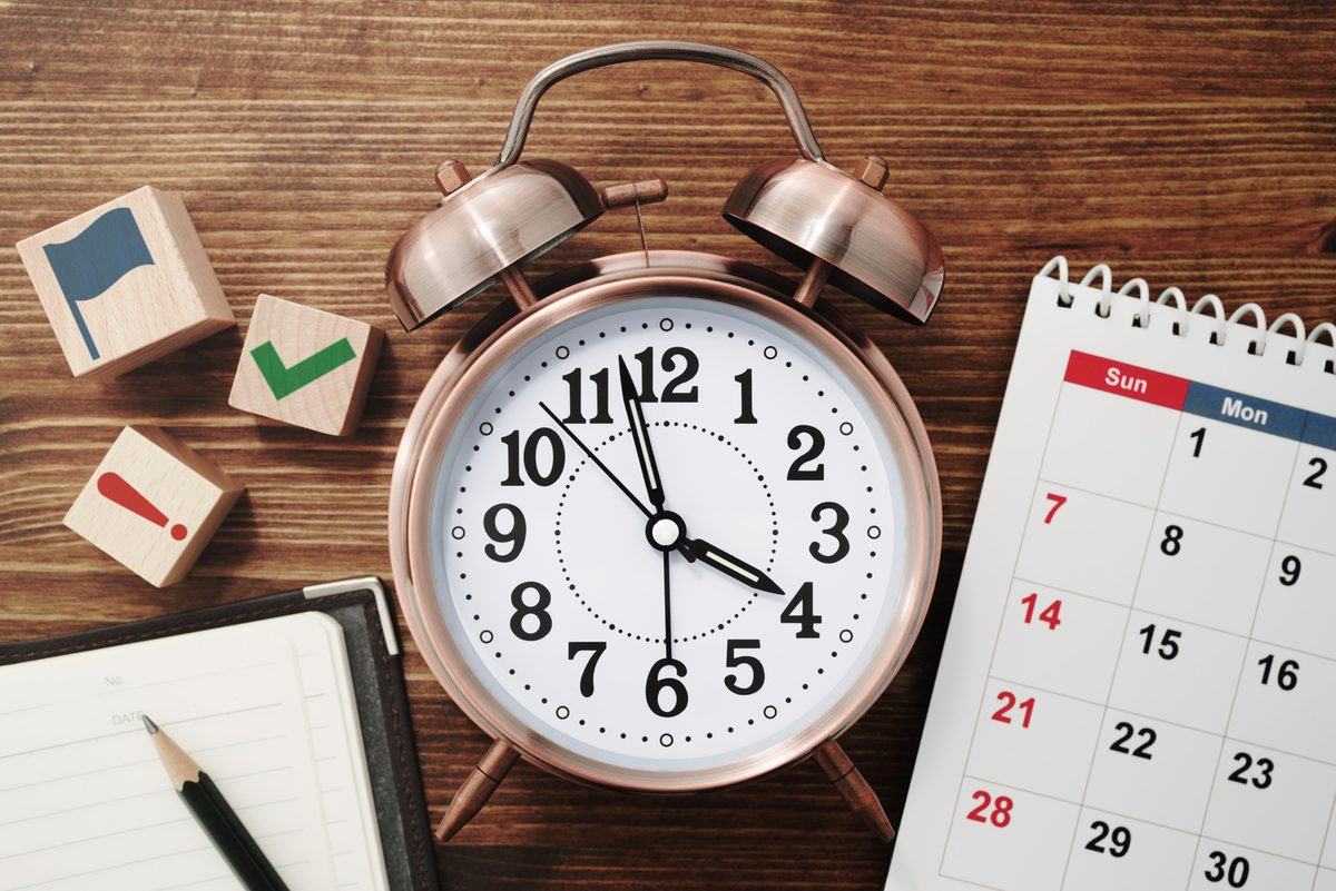 Reloj despertador junto a un calendario