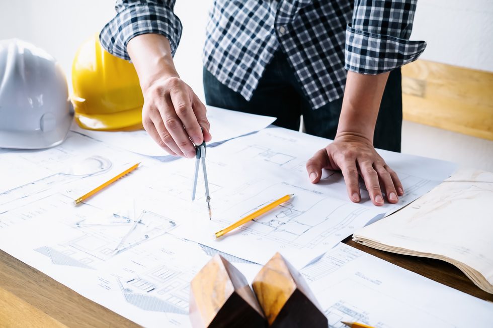 Planos de obra, casco de seguridad e instrumentos de dibujo técnico